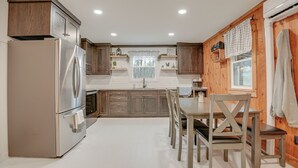 Una cocina moderna con armarios de madera, un refrigerador de acero inoxidable y un comedor con mesa y sillas de madera.