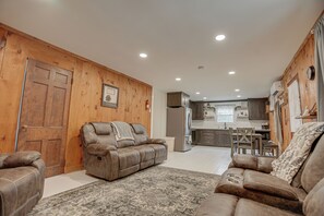 A modern living room with a leather sofa, a patterned rug, and wooden walls.