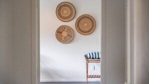 A room with a white door, three woven wall hangings, and a bed with a striped pillow. - Henry`s Bach with Wi-Fi, private rear garden for alfesco dining (Taupō)