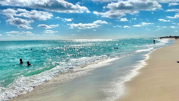 A beach with clear turquoise water, a sandy shore, and a partly cloudy sky. - Seven Palms Waterfront - Private Dock, Heated Pool & Lanai - Walk to Beach! (West Palm Beach)