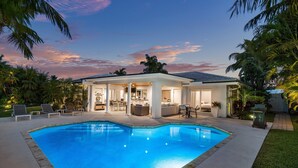 A modern house with a swimming pool, outdoor seating, and a patio area. - Seven Palms Waterfront - Private Dock, Heated Pool & Lanai - Walk to Beach! (West Palm Beach)