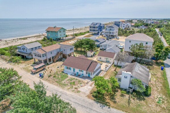 An aerial view of a coastal residential area with houses, a beach, and a clear sky.