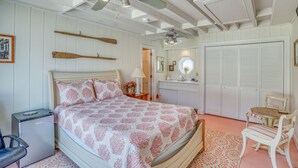 Ein Schlafzimmer mit Bett, Schreibtisch, Stuhl, Kleiderschrank und Deckenventilator.