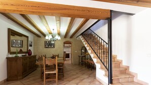 A spacious dining area with a wooden table and chairs, a kitchen in the background, and a staircase with a black railing. - Villa with 3 bedrooms, tennis court, pool and barbecue (Buger)
