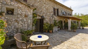 A stone building with a courtyard, outdoor seating, and potted plants. - Villa with 3 bedrooms, tennis court, pool and barbecue (Buger)