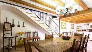 A dining area with a wooden table and chairs, a staircase with a black railing, and a chandelier. - Villa with 3 bedrooms, tennis court, pool and barbecue (Buger)