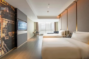 Una habitación de hotel moderna con una cama grande, un escritorio y vistas a la ciudad desde la ventana.