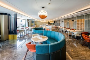 Un moderno vestíbulo de hotel con una zona de estar curva, un bar central y vistas a la ciudad.