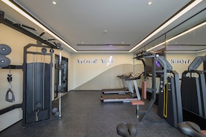 Un gimnasio con cintas de correr, máquinas de pesas y una pared con el rótulo 'ATOUR FIT'.