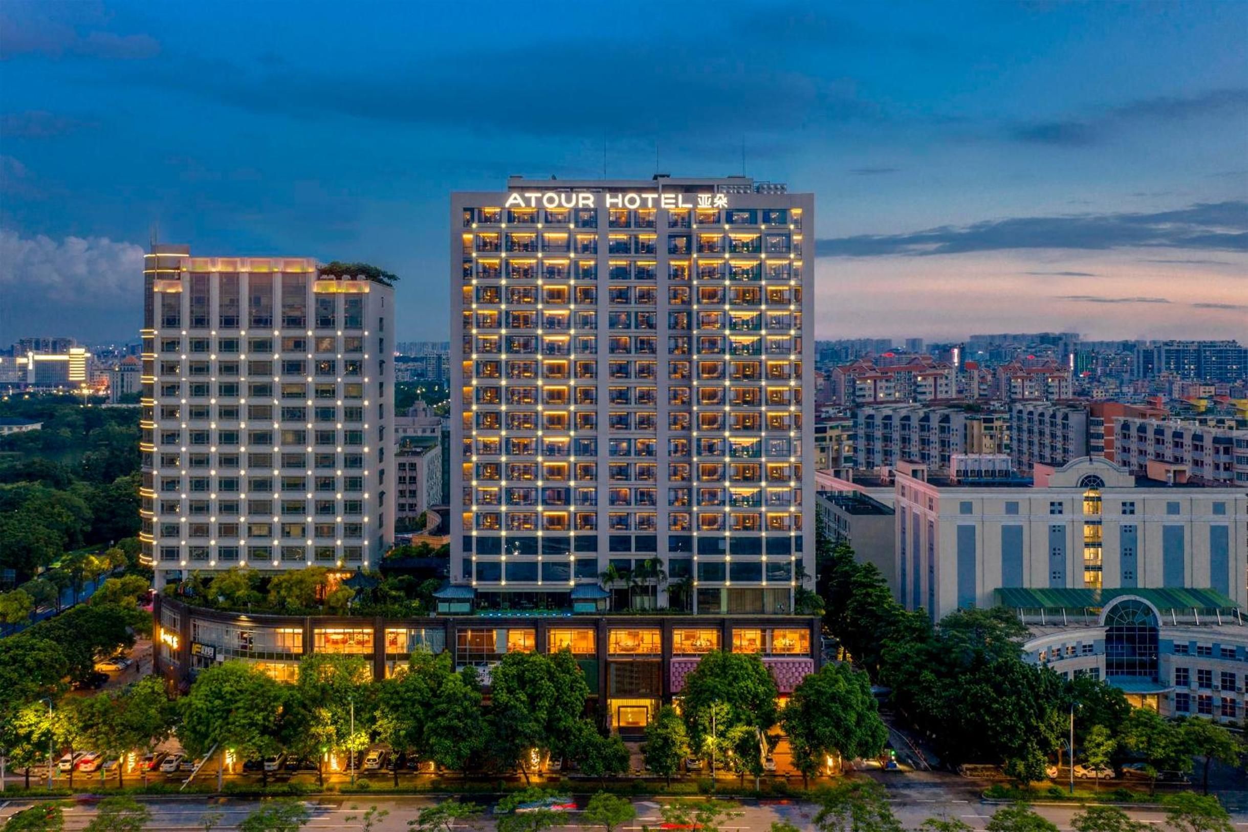 Un hotel de gran altura con varios pisos, un letrero llamativo en la parte superior y un paisaje urbano circundante.