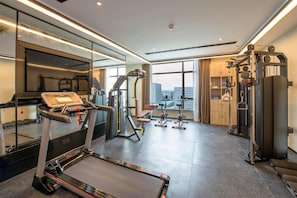 Un gimnasio moderno con una cinta de correr, máquinas de pesas y un espejo.