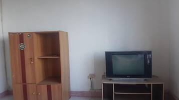 A wooden cabinet with a logo, a television on a stand, and a wall socket.