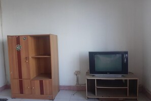 A wooden cabinet with a logo, a television on a stand, and a wall socket. - Spot ON 90535 Cimanuk Pavilion (Bengkulu)