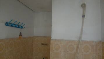 A bathroom with a shower, a towel rack, and a small shelf with toiletries.