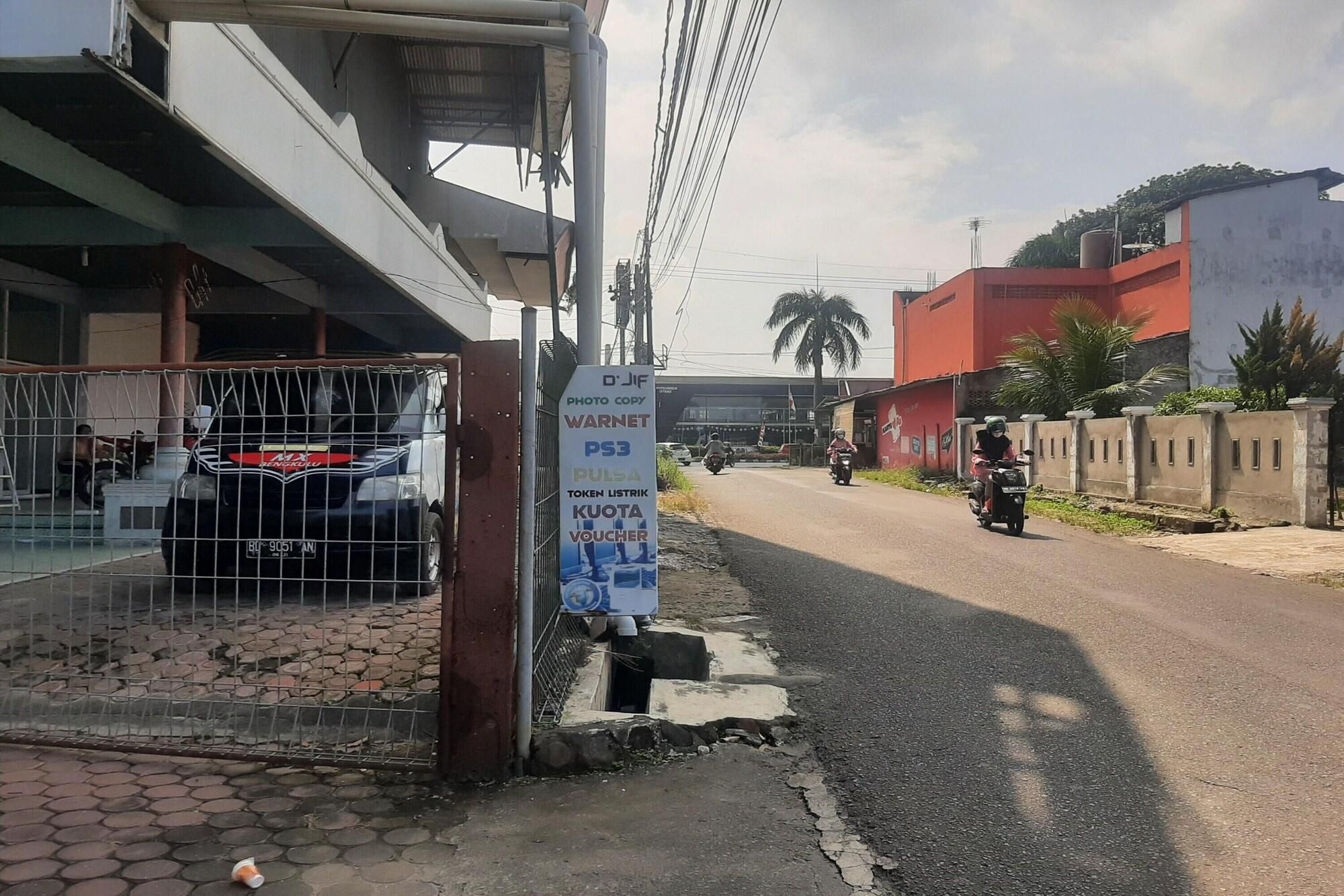 A street scene with a metal gate, a signboard, and a motorbike rider.