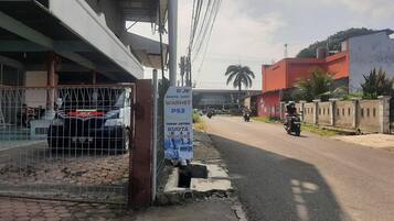 A street scene with a metal gate, a signboard, and a motorbike rider.