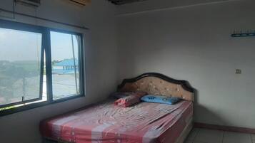 A bedroom with a bed, a window, and a view of buildings outside.
