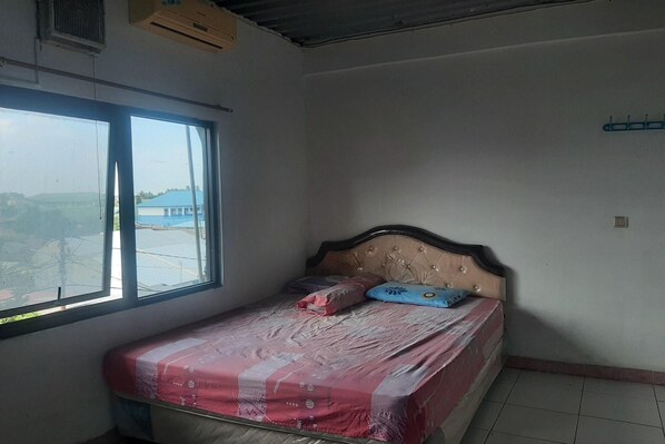 A bedroom with a bed, a window, and a view of buildings outside.