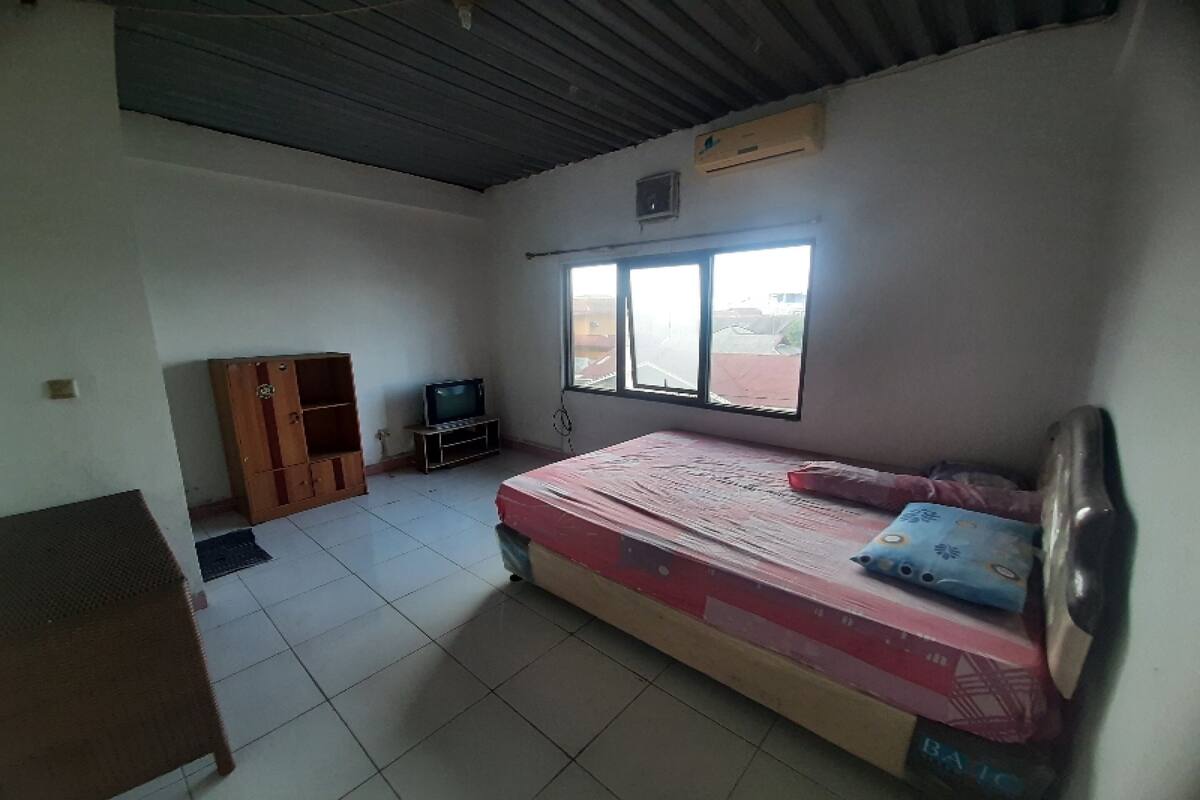 Ein Zimmer mit einem Bett, einem Fernseher, einem Kleiderschrank und einem Fenster.