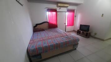 A bedroom with a bed, a television on a stand, and a door with curtains.