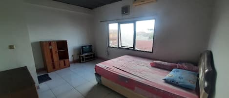 A room with a bed, a TV, a wardrobe, and a window.