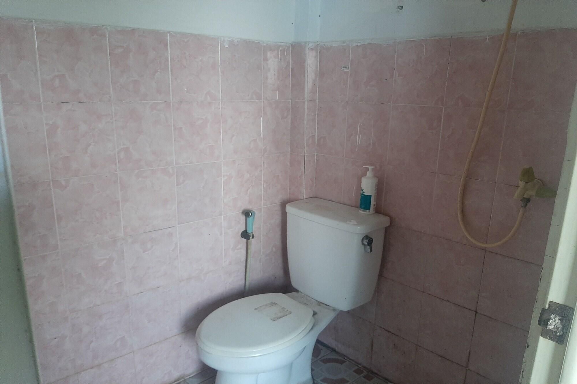 A small bathroom with a toilet, a shower, and a wall-mounted soap dispenser.