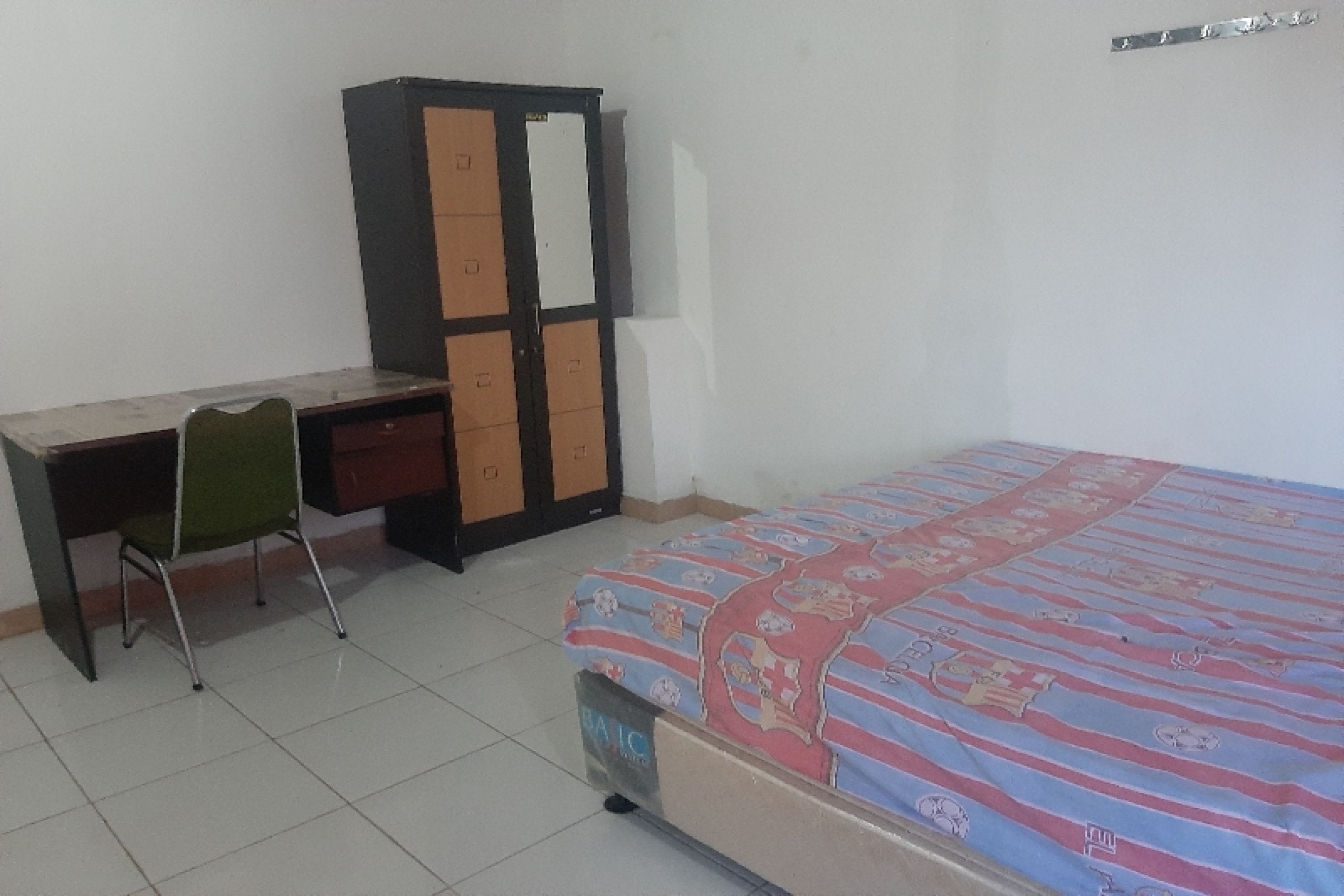 A bedroom with a bed, a desk, and a wardrobe.