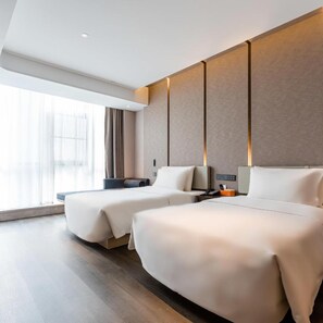 A hotel room with two beds, a large window, and a modern design.
