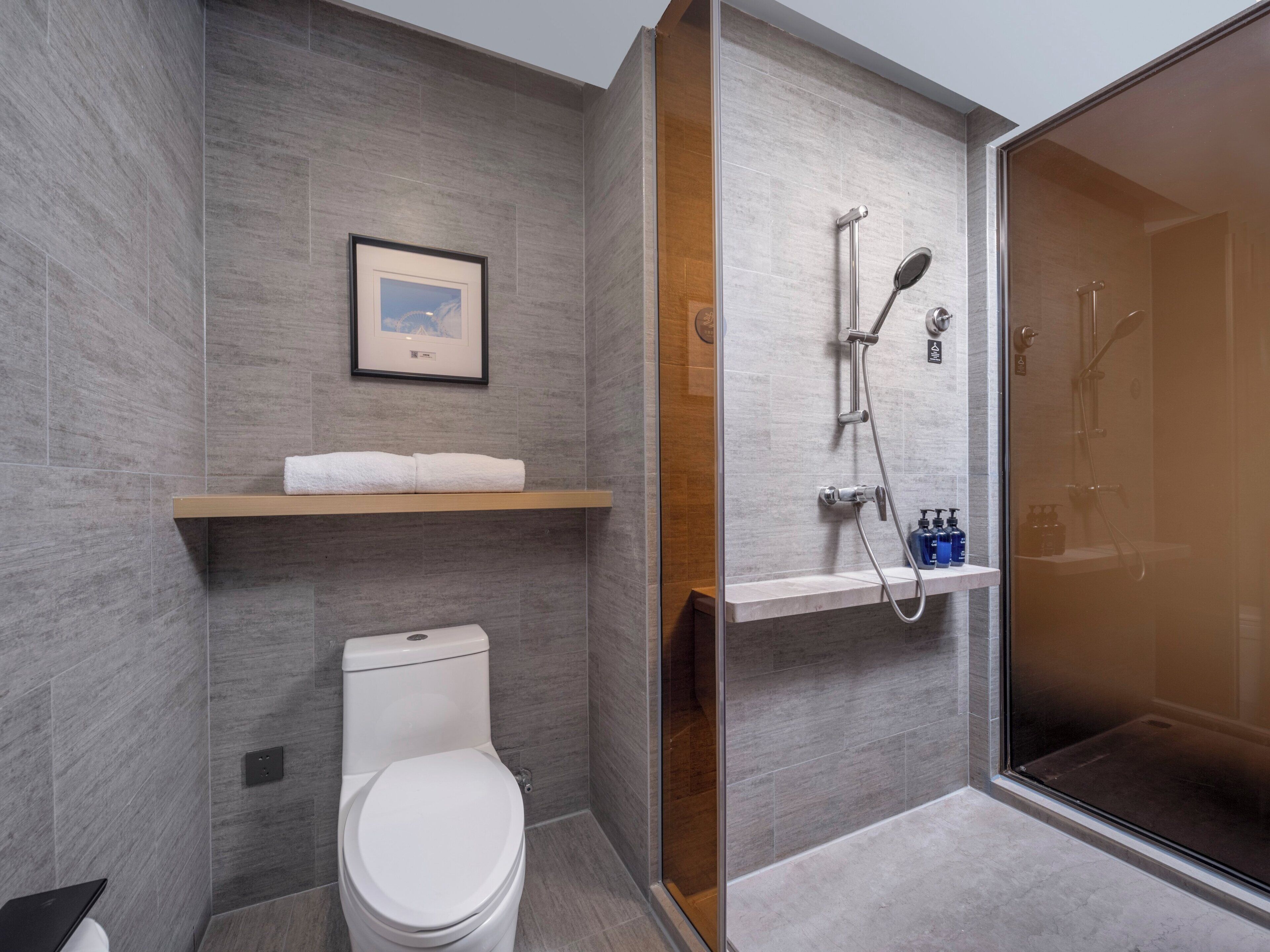 Ein modernes Badezimmer mit Toilette, Dusche und einem gerahmten Bild an der Wand.