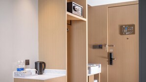 Habitación de hotel moderna con kitchenette, refrigerador pequeño, cafetera y dispensador de agua.