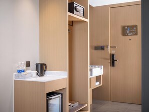 Habitación de hotel moderna con kitchenette, refrigerador pequeño, cafetera y dispensador de agua.
