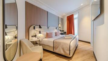 Una habitación de hotel moderna con una cama grande, un rincón de descanso y un espejo.