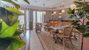 A dining area with wicker chairs and a patterned rug, a kitchen with hanging lights, and large windows. - Soho Boutique Turia (Valencia)