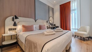 A hotel room with a large bed, a bedside table, a chair, a desk with a chair, and a window with curtains. - Soho Boutique Turia (Valencia)