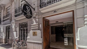 A boutique hotel entrance with a sign, a wooden door, and bicycles parked outside. - Soho Boutique Turia (Valencia)