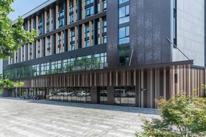 A modern building with a glass facade, a sign reading 'TOUR LIGHT,' and a paved entrance area. - Shanghai Baoshan Changjiang Road Atour Light Residence Hotel (Shanghai)