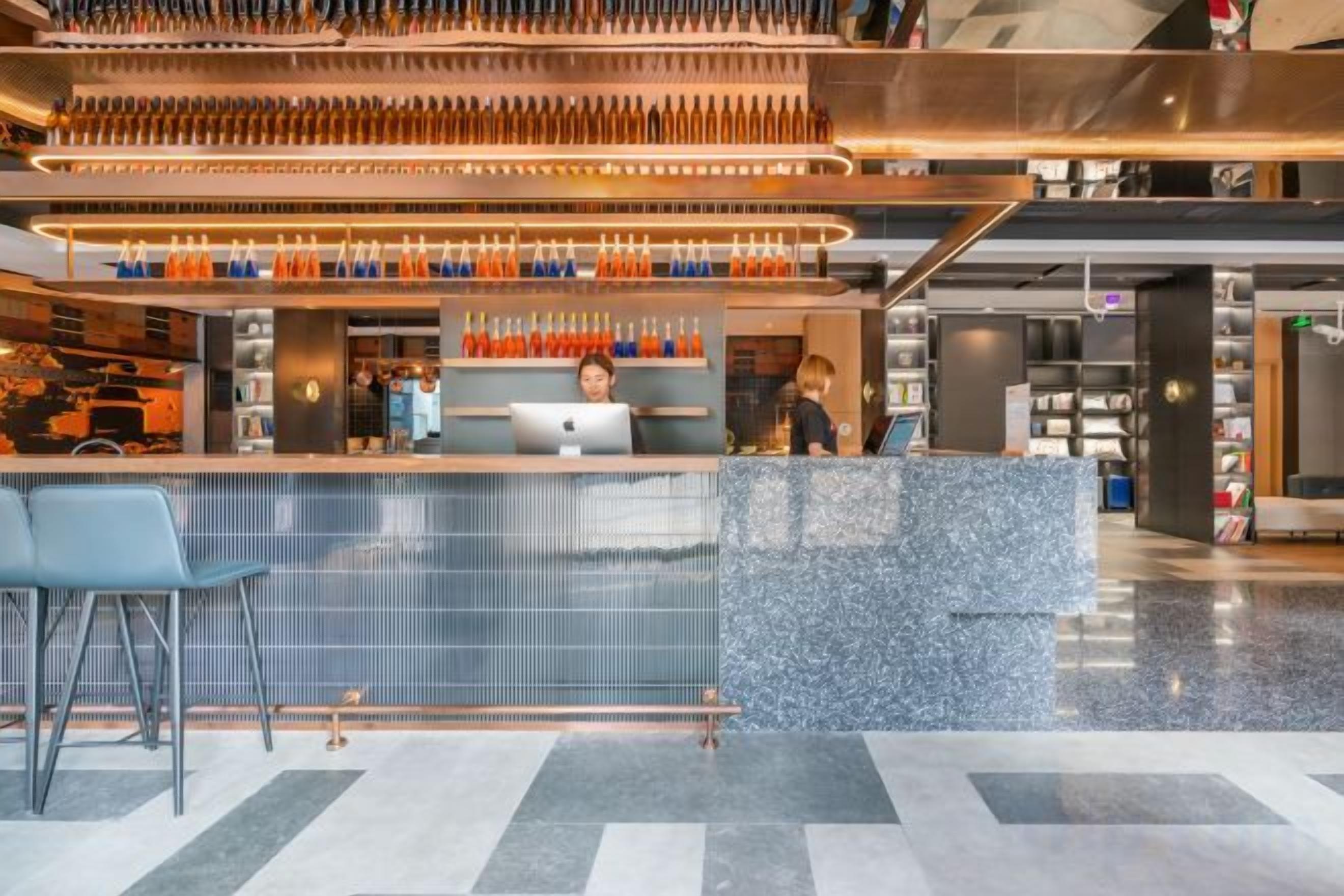 A modern bar area with a counter, seating, and a variety of bottles.