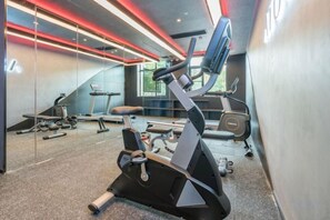 Un gimnasio con equipo de ejercicio, cinta de correr y pared de espejos.