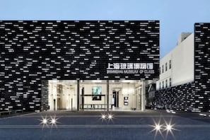 A building facade with a grid of names, a large entrance, and a sign above the entrance. - Shanghai Baoshan Changjiang Road Atour Light Residence Hotel (Shanghai)