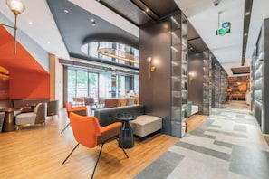 A modern interior with a curved ceiling, seating area with orange chairs, and a visible kitchen in the background.
