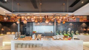 Una cucina moderna con pentole di rame appese al soffitto, un piano di lavoro in marmo e diversi utensili e elettrodomestici da cucina.