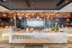 A modern kitchen with copper pots hanging from the ceiling, a marble countertop, and various kitchen utensils and appliances. - Shanghai Baoshan Changjiang Road Atour Light Residence Hotel (Shanghai)