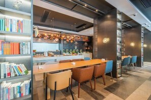 Un comedor moderno con una larga mesa de madera, sillas azules y estanterías llenas de libros.