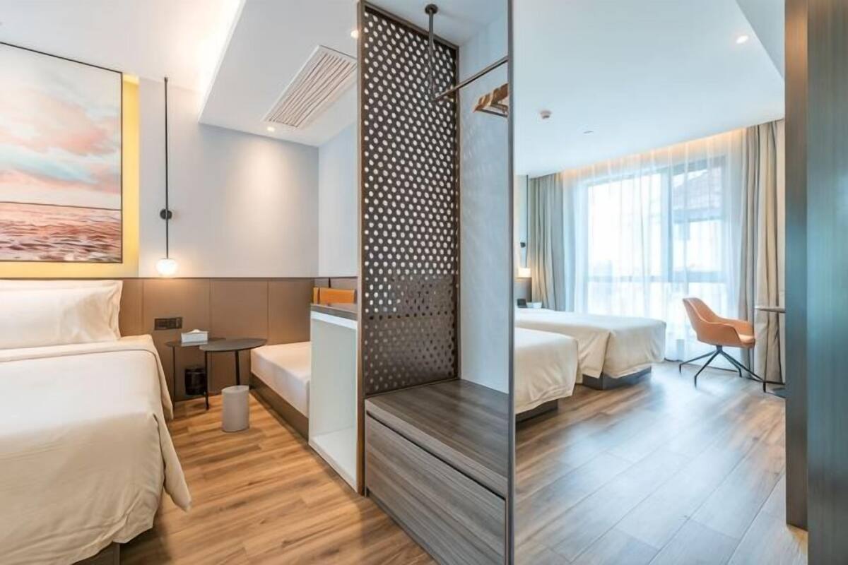 A hotel room with a bed, a desk, a chair, and a large window.