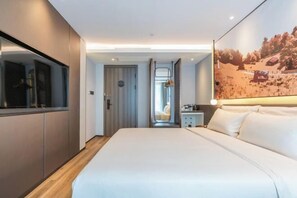 A modern hotel room with a large bed, a walk-in closet, a bathroom, and a mural on the wall.