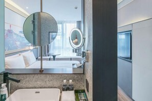 A modern hotel room with a large bed, a round mirror, a small table, and a bathroom with a sink and toiletries. - Shanghai Baoshan Changjiang Road Atour Light Residence Hotel (Shanghai)