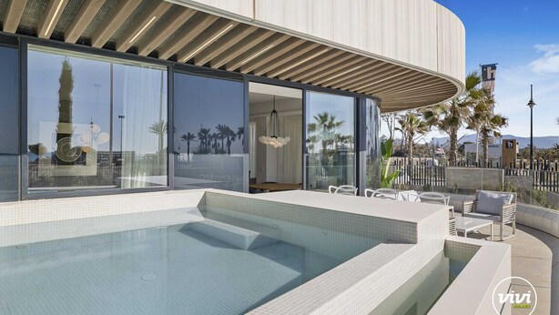 A modern building with a swimming pool, large windows, and outdoor seating.