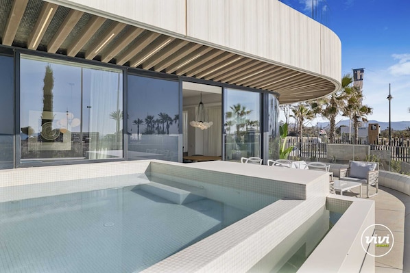 A modern building with a swimming pool, large windows, and outdoor seating.