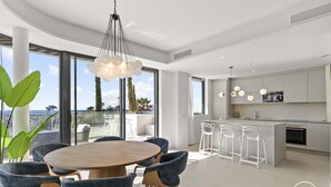 A modern kitchen with a central island, bar stools, and a dining area with round table and chairs.