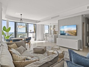 A modern living room with a large TV, comfortable seating, and a balcony with a view. - Sunrise | Private Pool - Beachfront - Terrace (Torremolinos)